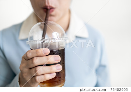 Asian young woman drinking iced black coffee in a plastic cup,take away package,using plastic straws to drink beverage,concept of stop using plastic campaign,ecology problem,environmental pollution Asian young woman drinking iced black coffee in a plastic cup,take away package,using plastic straws to drink beverage,concept of stop using plastic campaign,ecology problem,environmental pollution 76402903