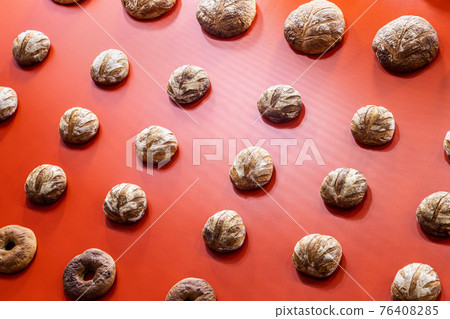 round loaves of bread hang on the red wall 76408285