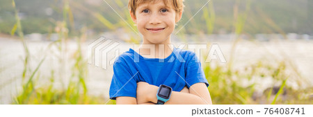 Boy uses kids smart watch outdoor against the background of the garden BANNER, LONG FORMAT 76408741