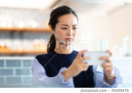 A woman looking at her smartphone in the living room A woman looking at her smartphone in the living room 76409476