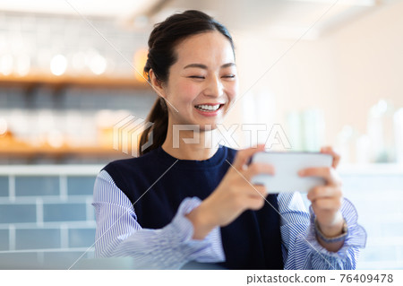 A woman looking at her smartphone in the living room A woman looking at her smartphone in the living room 76409478