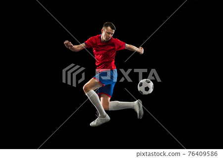 Young Caucasian soccer football player practicing isolated on black background. 76409586