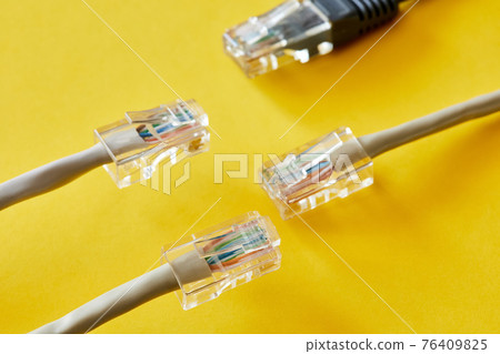 Ethernet cables with RJ45 plug on yellow background. Close-up, selective focus 76409825