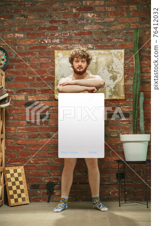 Portrait of young man with blank sign like social media screen sitting at home. Portrait of young man with blank sign like social media screen sitting at home. 76412032
