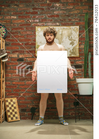 Portrait of young man with blank sign like social media screen sitting at home. Portrait of young man with blank sign like social media screen sitting at home. 76412033