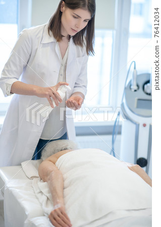 Female massage therapist doing back massage procedures to a woman 76412034