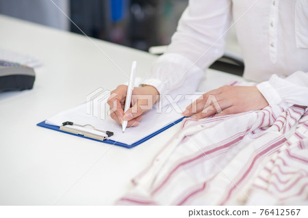 Female hands writing with pen on sheet Female hands writing with pen on sheet 76412567