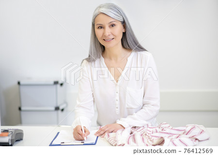 Good looking woman taking clothes for dry cleaning Good looking woman taking clothes for dry cleaning 76412569