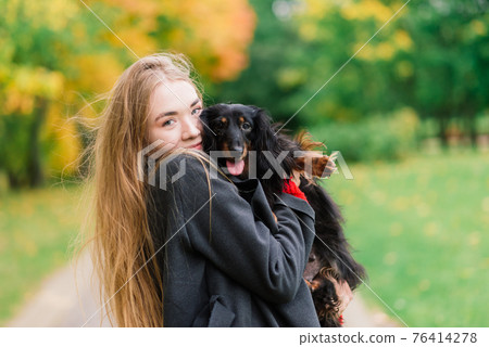 Happy woman holding her little dog in arms Happy woman holding her little dog in arms 76414278