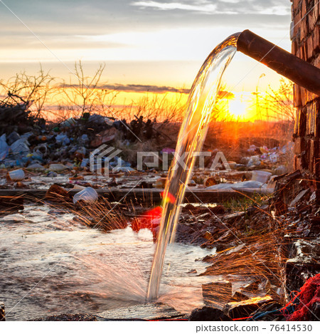 Water pours out of an old rusty pipe 76414530