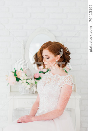 Portrait of red haired girl wearing wedding dress against a white studio background. Portrait of red haired girl wearing wedding dress against a white studio background. 76415163