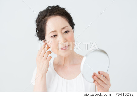 看鏡子和檢查她的髮型的資深婦女 76416282