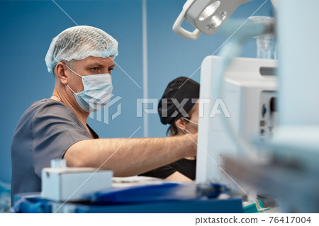 Anesthesiologist keeping track of vital functions of the body during cardiac surgery. Surgeon looking at medical monitor during surgery. Doctor checking monitor for patient health status. 76417004