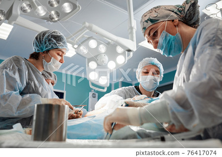 Blepharoplasty plastic surgery operation for modifying the eye region of the face in medical clinic. 2 doctors do plastic cosmetic operation for woman. Surgeon sutures the eyelid Blepharoplasty plastic surgery operation for modifying the eye region of the face in medical clinic. 2 doctors do plastic cosmetic operation for woman. Surgeon sutures the eyelid 76417074