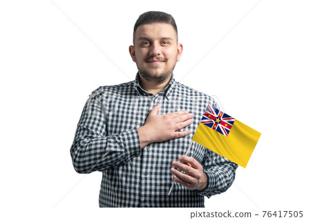 White guy holding a flag of Niue and holds his hand on his heart isolated on a white background With love to Niue White guy holding a flag of Niue and holds his hand on his heart isolated on a white background With love to Niue 76417505