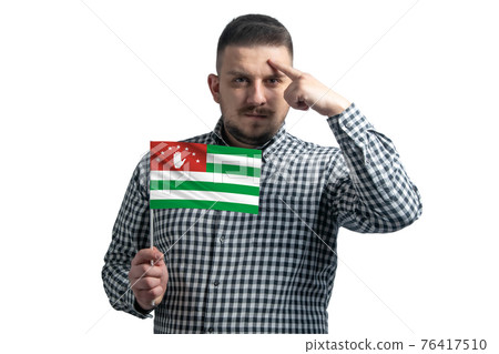 White guy holding a flag of Abkhazia and a finger touches the temple on the head isolated on a white background White guy holding a flag of Abkhazia and a finger touches the temple on the head isolated on a white background 76417510