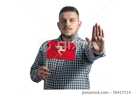 White guy holding a flag of Isle of Man and with a serious face shows a hand stop sign isolated on a white background White guy holding a flag of Isle of Man and with a serious face shows a hand stop sign isolated on a white background 76417514
