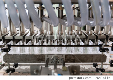 The machine fills plastic bottles with water. Close-up. 76418116