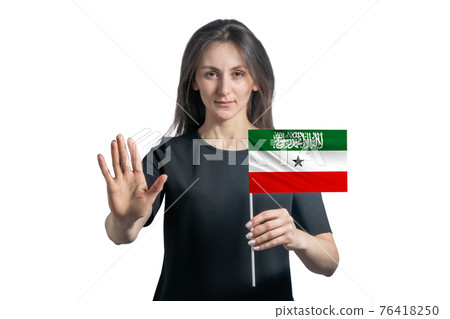 Happy young white woman holding flag of Kurdistan and with a serious face shows a hand stop sign isolated on a white background Happy young white woman holding flag of Kurdistan and with a serious face shows a hand stop sign isolated on a white background 76418250