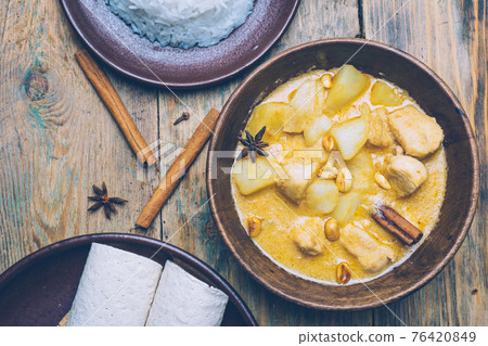 Massaman curry (chicken curry) whith cinnamon sticks and plane riсe on wooden background. Coconut milk curry. Massaman curry (chicken curry) whith cinnamon sticks and plane riсe on wooden background. Coconut milk curry. 76420849
