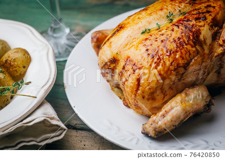 Roasted chicken with thyme served on white plate with potatoes, oranges and spices on wooden table. Thanksgiving or Christmas dinner. Top view 76420850