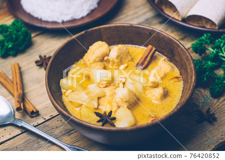 Massaman curry (chicken curry) whith cinnamon sticks and plane riсe on wooden background. Coconut milk curry. 76420852