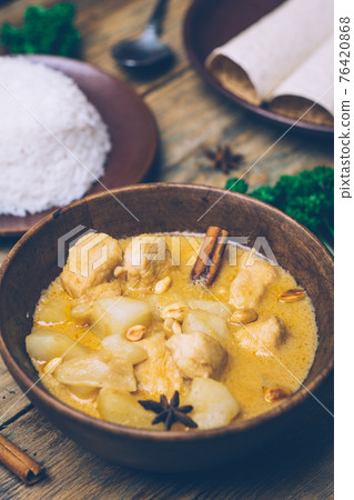 Massaman curry (chicken curry) whith cinnamon sticks and plane riсe on wooden background. Coconut milk curry. 76420868