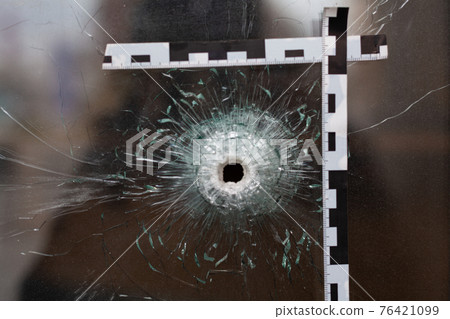 bullet holes in a glass shop window marked with a police tape bullet holes in a glass shop window marked with a police tape 76421099