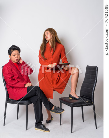 Mature Asian businesswoman and weird Asian woman therapist having consultation together 76421589