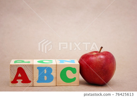 English ABC alphabet letters next to the red apple . 76425613