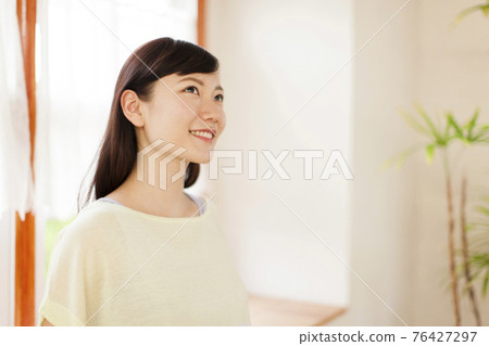 Woman by the window 76427297