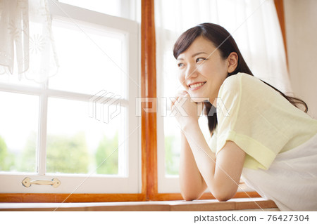 Woman by the window 76427304