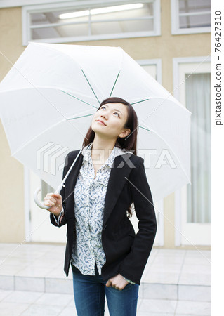 A woman holding an umbrella 76427310