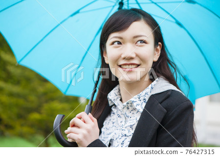 A woman holding an umbrella 76427315