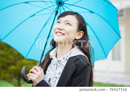 A woman holding an umbrella 76427316