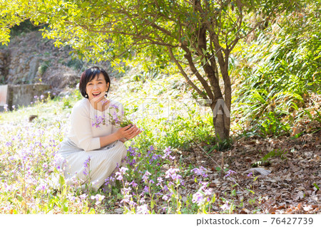 Middle-aged woman enjoying spring flowers Middle-aged woman enjoying spring flowers 76427739
