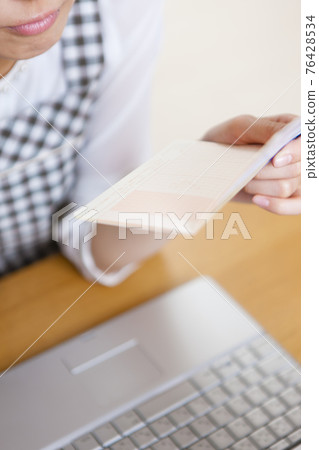 A woman holding a household account book 76428534