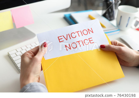 Woman sitting at table and holding eviction letter closeup Woman sitting at table and holding eviction letter closeup 76430198