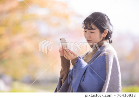 A woman using a smartphone in an autumn park (problem) A woman using a smartphone in an autumn park (problem) 76430938