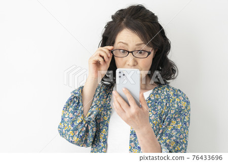 戴老花鏡，看著智能手機的老婦人 76433696