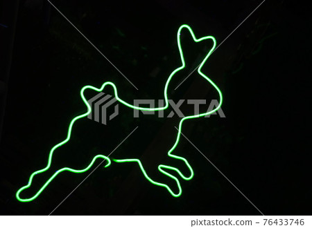 Green neon tube bending into a rabbit shape for decorating the place on black background. 76433746