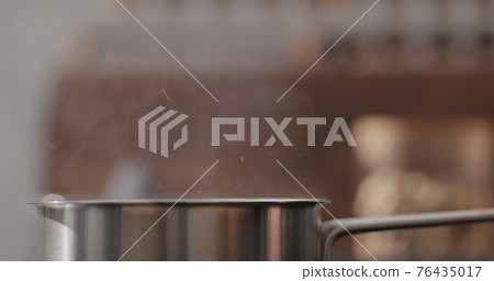 steam rising from saucepan with boiling water on kitchen closeup 76435017