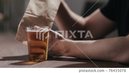 Man drinking amber color fizzy drink with bag of potato chips Man drinking amber color fizzy drink with bag of potato chips 76435078