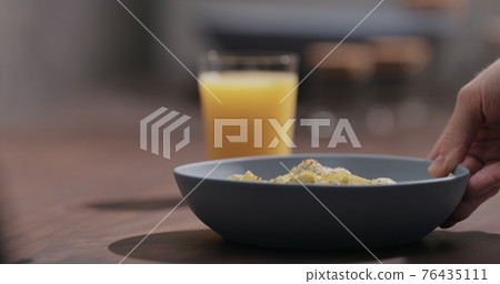 man put blue bowl with pesto fettuccine on walnut table with orange juice 76435111