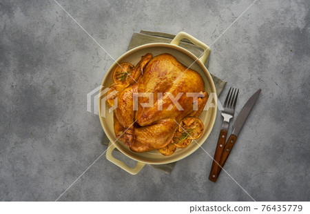 Roasted homemade chicken with lemons and rosemary in a baking dish. Top view with copy space Roasted homemade chicken with lemons and rosemary in a baking dish. Top view with copy space 76435779
