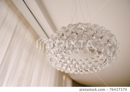 Stylish hi-tech chandelier made of transparent acrylic balls. White light interior style. Stylish hi-tech chandelier made of transparent acrylic balls. White light interior style. 76437379
