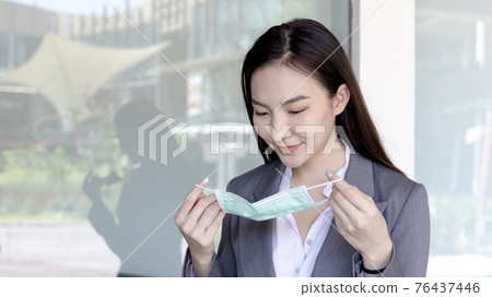 Young Asian woman has a mask ready to wear. Prevention of pathogens or epidemics of the CORONA VIRUS, Initial protection. Helping to reduce the spread of germs, Face mask, Safety first Young Asian woman has a mask ready to wear. Prevention of pathogens or epidemics of the CORONA VIRUS, Initial protection. Helping to reduce the spread of germs, Face mask, Safety first 76437446
