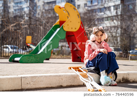 teen girl with a broken leg on crutches in the playground. teen girl with a broken leg on crutches in the playground. 76440596