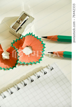 Green wooden pencils and notepad opened with pencil sharpener 76442333