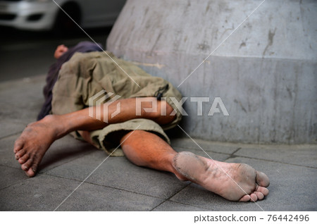Homeless man sleeping on pavement floor 76442496